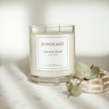 Candle labeled 'Bordeaux French Pear' on a soft background